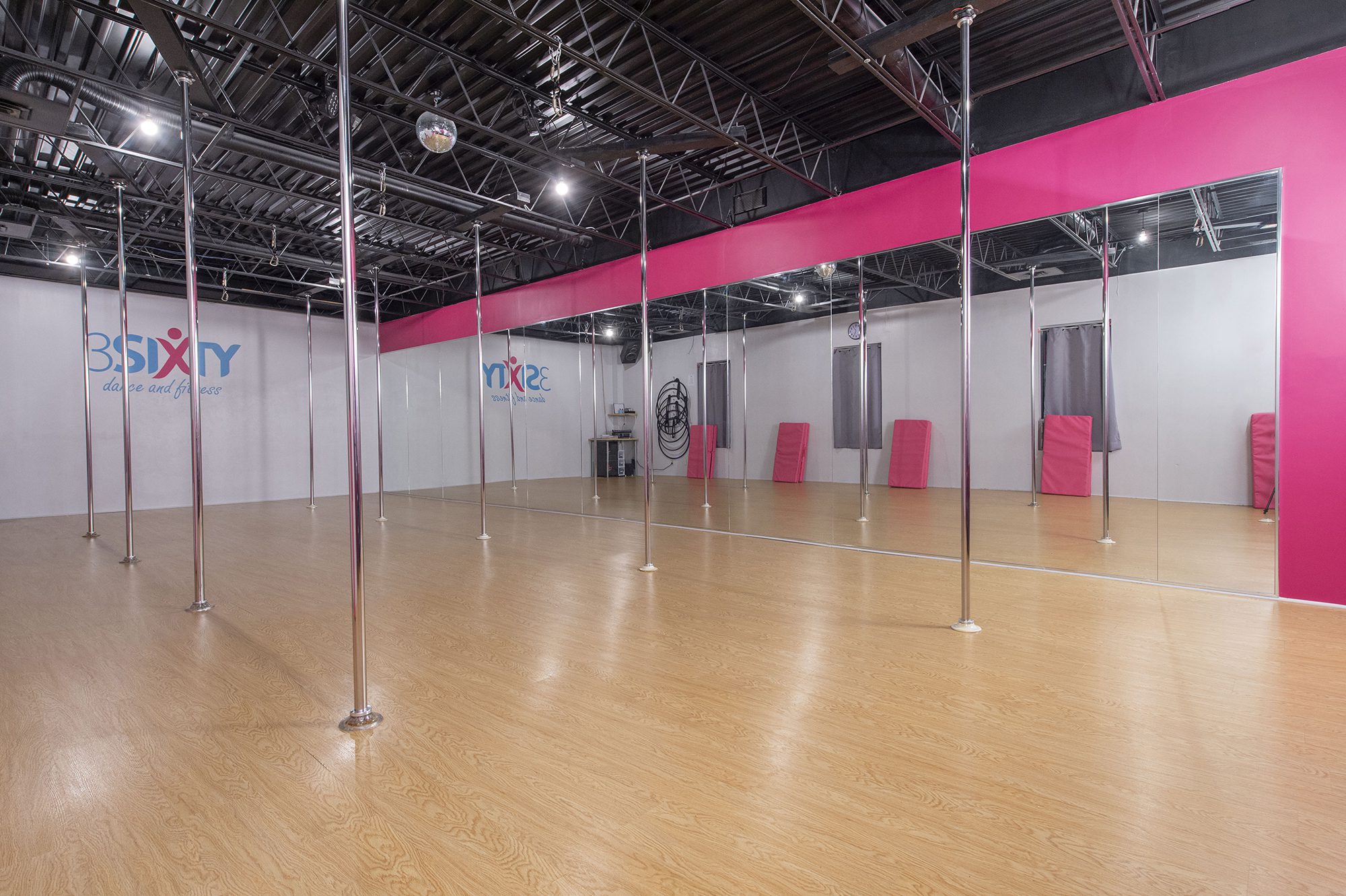 The empty pole room at 3Sixty's Clyde studio, a long row of poles over a wooden floor